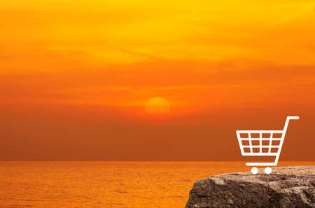 Shopping cart flat icon on rock mountain over sunset sky and sea, Business shop online conceptの写真素材