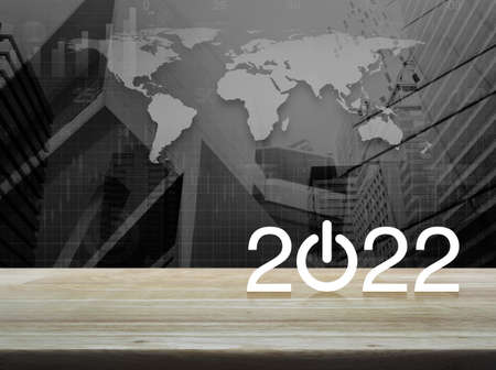 2022 start up business flat icon on wooden table over black and white world map with modern city tower and skyscraper, Happy new year 2022 cover conceptの写真素材
