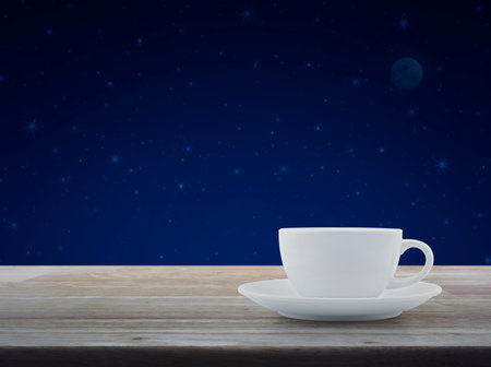 White coffee cup on wooden table over fantasy night sky and moonの写真素材
