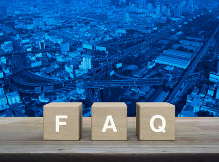 FAQ letter on wood block cubes on wooden table over modern office city tower, street, expressway and skyscraper, Business customer service and support conceptの写真素材