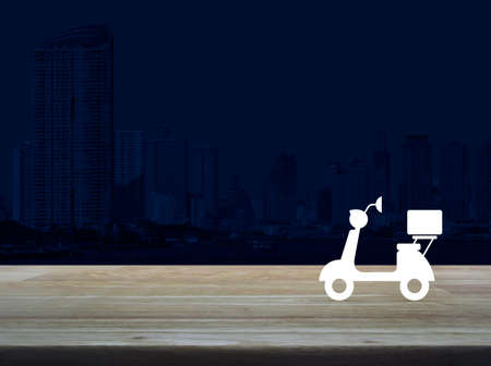 Motorcycle flat icon on wooden table over modern office city tower and skyscraper, Business delivery service conceptの写真素材
