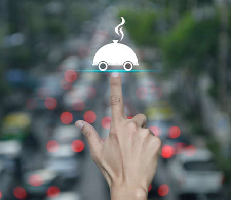 Hand pressing restaurant cloche flat icon over blur of rush hour with cars and road in city, Business food delivery online conceptの写真素材