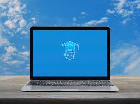 E-learning flat icon on modern laptop computer monitor screen on wooden table over blue sky with white clouds, Business study online conceptの写真素材
