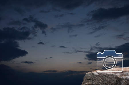 Camera flat icon on rock mountain over sunset sky, Business camera service conceptの写真素材
