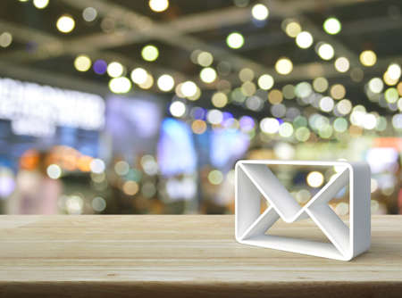 Mail 3d icon on wooden table over blur light and shadow of shopping mall, Business customer service and support online conceptの写真素材