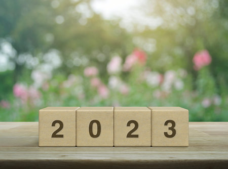 2023 letter on wood block cubes on wooden table over blur pink flower and tree in garden, Happy new year 2023 cover conceptの写真素材