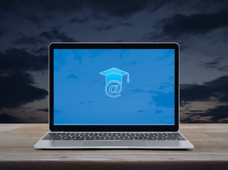 E-learning flat icon on modern laptop computer monitor screen on wooden table over sunset sky, Business study online conceptの写真素材