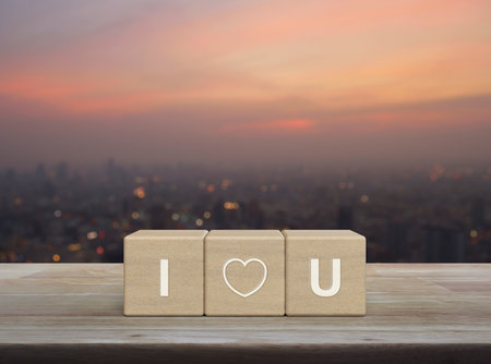 I love you letter on wood block cubes on wooden table over blur of cityscape on warm light sundown, Valentines day conceptの写真素材