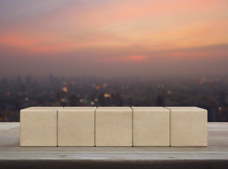 Five wood block cubes on wooden table over blur of cityscape on warm light sundownの写真素材