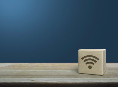 Wifi icon on wood block cube on wooden table over light blue wall, Technology internet communication conceptの写真素材