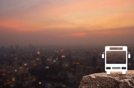 Bus icon on rock mountain over blur of cityscape on warm light sundown, Business transportation service conceptの写真素材