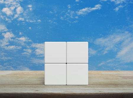 Four white block cubes on wooden table over blue sky with white cloudsの写真素材
