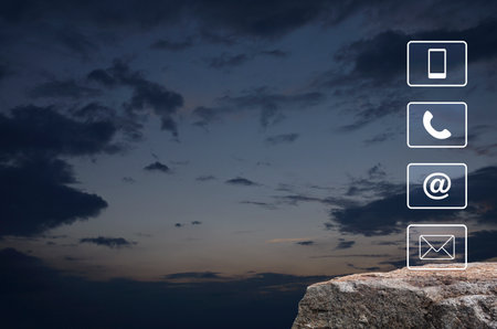 Telephone, mobile phone, address and email icon on rock mountain over sunset sky, Business customer service and support online conceptの写真素材