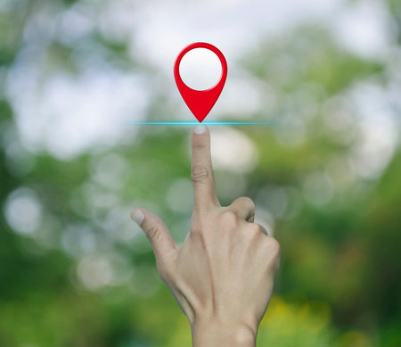 Hand pressing map pin point location button over blur green tree in park, Map pointer navigation conceptの写真素材