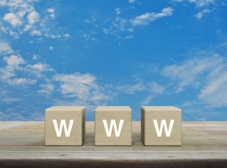 WWW letter on wood block cubes on wooden table over blue sky with white clouds, Searching system and internet conceptの写真素材
