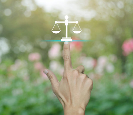 Hand pressing law flat icon over blur pink flower and tree in park, Business legal service conceptの写真素材