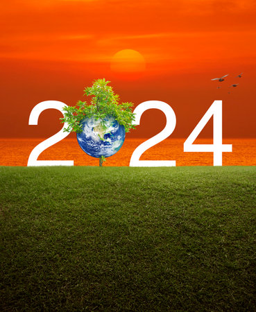 2024 white text with planet and tree on green grass field over sunset sky and sea, Happy new year 2024 ecological cover, Save the earth concept, Elements of this image furnishedの写真素材