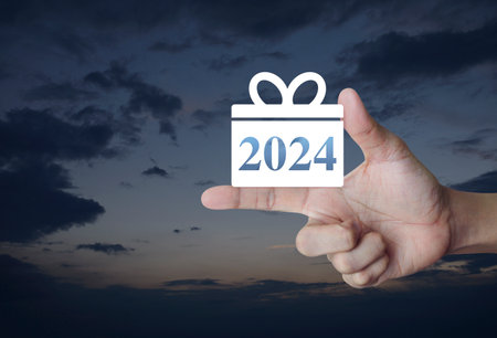 Gift box happy new year 2024 flat icon on finger over sunset sky, Business shopping online conceptの写真素材