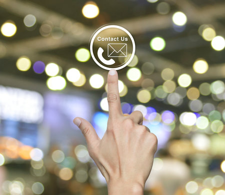 Hand pressing telephone and email icon button over blur light and shadow of shopping mall, Business...