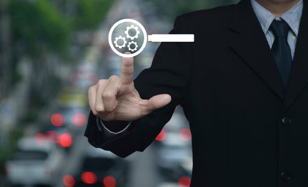 Businessman pressing seo flat icon over blur of rush hour with cars and road in city, Search engine optimization conceptの写真素材