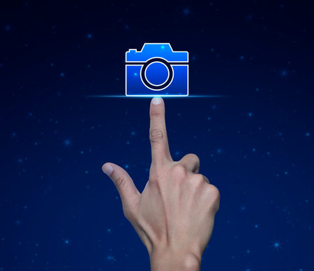 Hand pressing camera flat icon over fantasy night sky, Business camera service conceptの写真素材