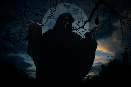 Grim reaper standing over cross, church, crow, bat, birds, dead tree, full moon and sunset sky, Halloween mystery conceptの写真素材