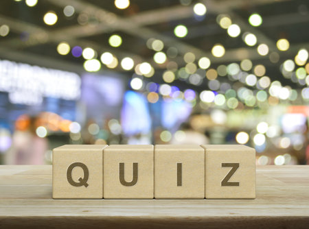 Quiz letter on wood block cubes on wooden table over blur light and shadow of shopping mall, Examination or test conceptの写真素材