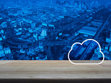 Cloud computing icon with copy space on wooden table over modern office city tower and skyscraper,...