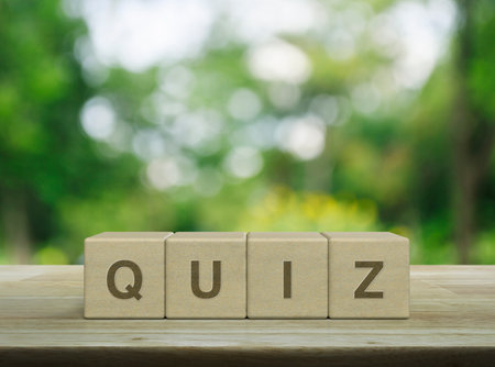 Quiz letter on wood block cubes on wooden table over blur green tree in park, Examination or test conceptの写真素材
