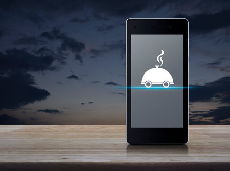 Restaurant cloche flat icon on modern smart mobile phone screen on wooden table over sunset sky, Business food delivery online conceptの写真素材