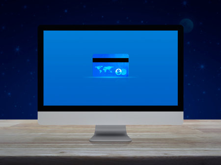 Credit card on modern computer monitor screen on wooden table over fantasy night sky and moon,...