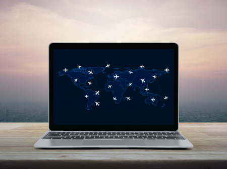 Flight routes airplanes connection and world map on laptop computer screen on table over city at sunset sky, vintage style, Business airplane transportation networkの写真素材
