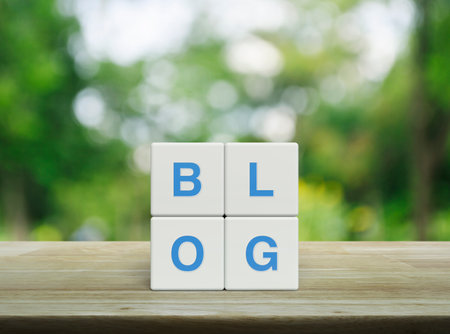 Blog letter on white block cubes on wooden table over blur green tree in park, Technology communication conceptの写真素材