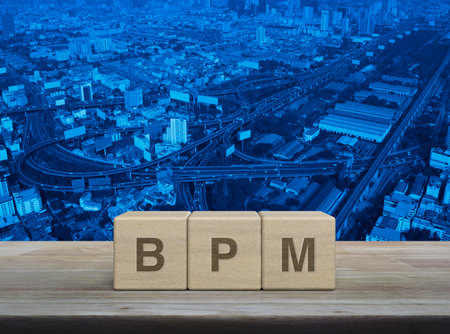 BPM acronym letter on wood block cubes on wooden table over modern city tower, street, expressway and skyscraper, Business process management conceptの写真素材