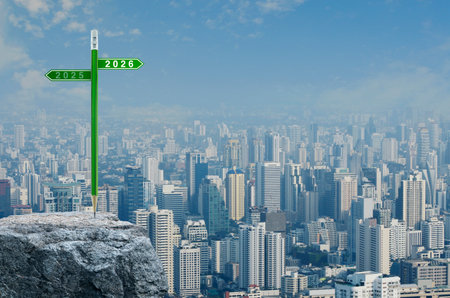 2026 and 2025 direction sign plate with green pencil on rock mountain over modern city tower, office building and skyscraper, Business happy new year 2026 strategy and planning conceptの写真素材