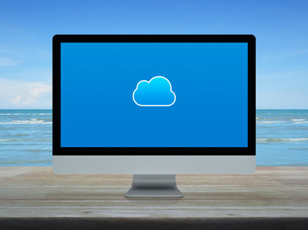 Cloud computing flat icon on modern computer monitor screen on wooden table over tropical sea and...