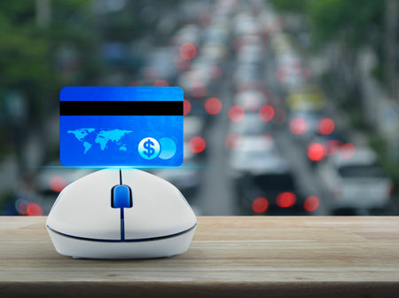 Credit card on wireless computer mouse on wooden table over blur of rush hour with cars and road, Online e-payment concept, Elements of this image furnished by NASAの写真素材