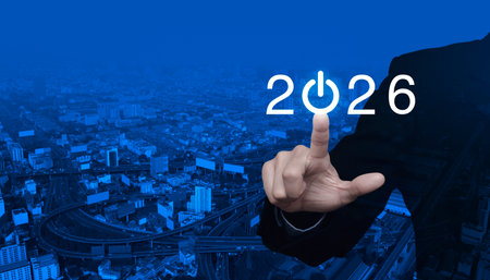 Businessman pressing 2026 start up business flat icon over modern city tower, street, expressway and...