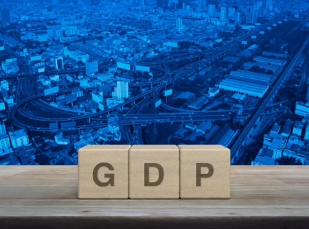 GDP acronym letter on wood block cubes on wooden table over modern city tower, street, expressway and skyscraper, Gross domestic product conceptの写真素材