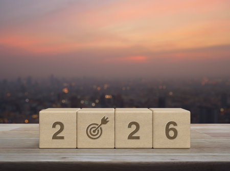 2026 letter with goal flat icon on wood block cubes on wooden table over blur of cityscape on warm light sundown, Happy new year 2026 success conceptの写真素材