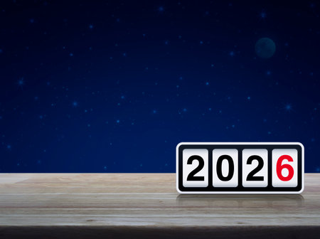 Retro flip clock with 2026 text on wooden table over fantasy night sky and moon, Happy new year 2026...