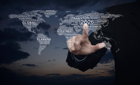 Businessman pressing 2026 start up flat icon with global business words world map over sunset sky,...