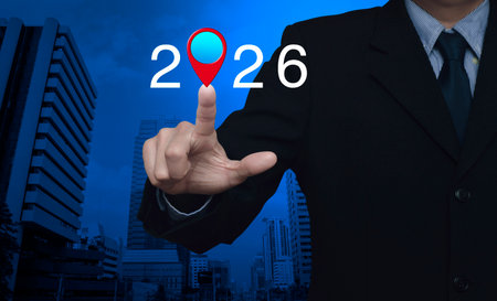 Businessman pressing 2026 letter with map pin location icon over modern office city tower and...