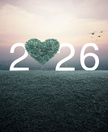 Green tree in the shape of heart love with 2026 white text on green grass field over aerial view of...