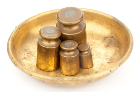Three brass old weights on a golden plateの写真素材
