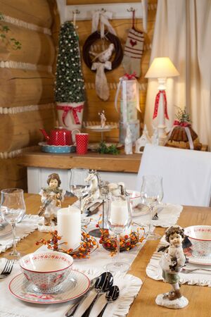 christmas table set with candles, sculptures and christmas treeの写真素材