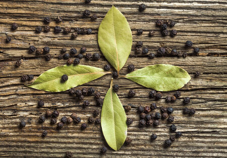 Four bay leaves and black pepper on old wood   の写真素材