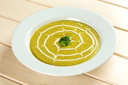 Broccoli vegetable soup cream in white plate on green and white backgroundの写真素材