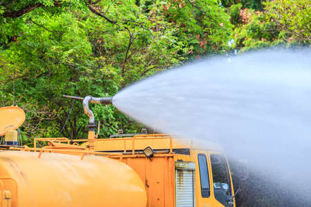 Yellow Water Tanker Watering Trees in a Gardenの写真素材