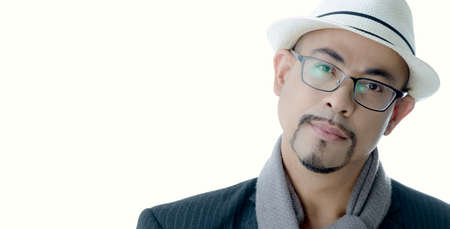 Young man smart business glasses, white hat handsome good-looking beautiful mustache look smart international very cool wear black suit ,gray scarf photographer in studio on white isolate backgroundの写真素材